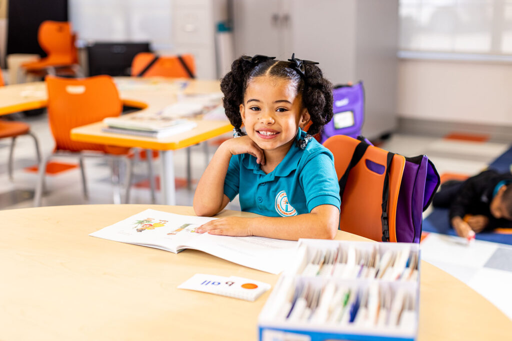 Young student smiling with book in classroom
