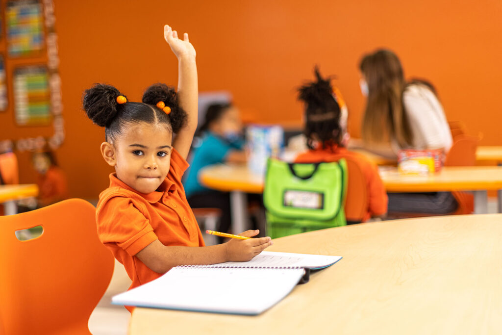 Student raising hand in colorful classroom setting