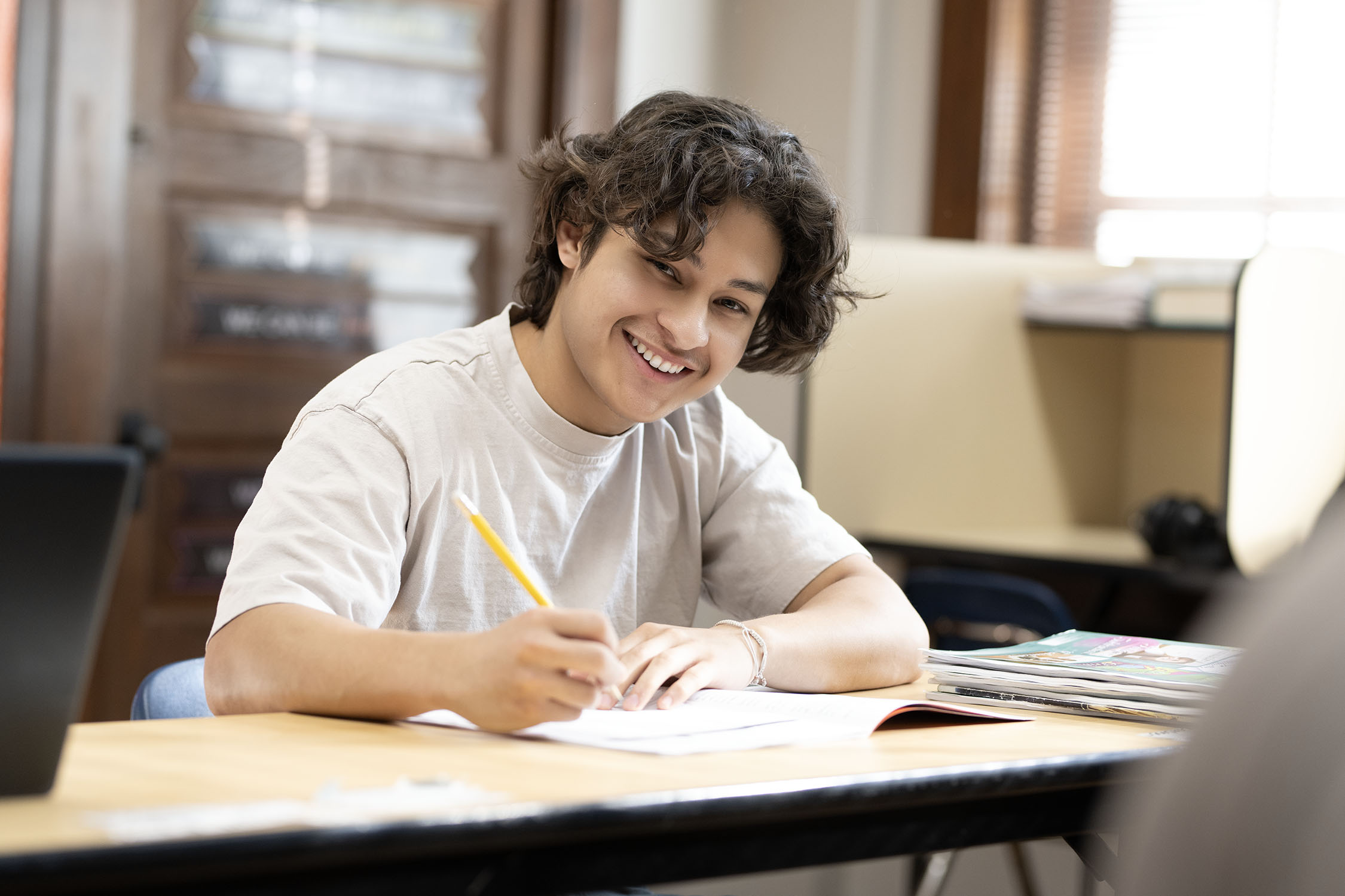 Happy student writing notes in a classroom setting.
