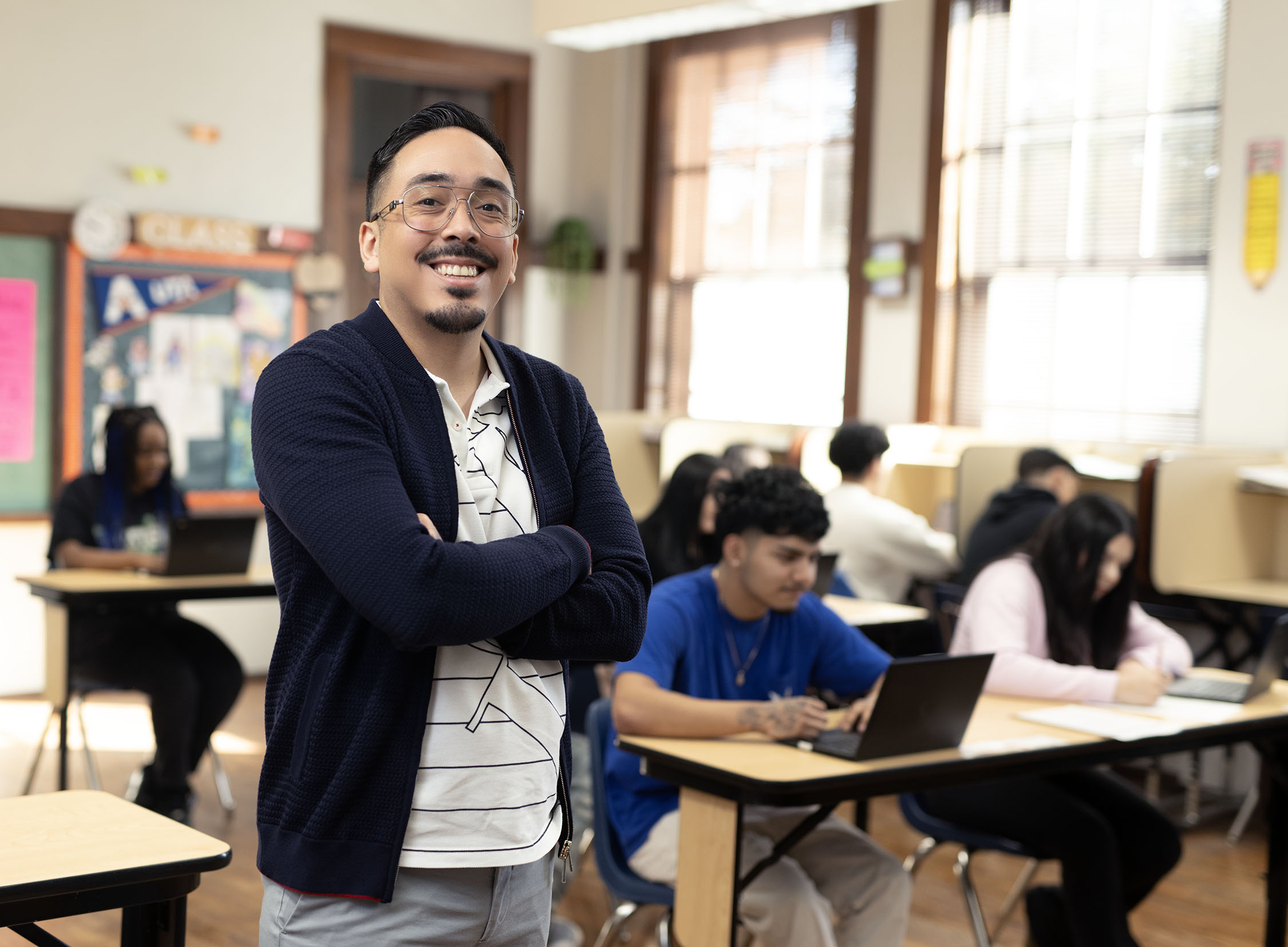 Confident teacher standing in a high school classroom