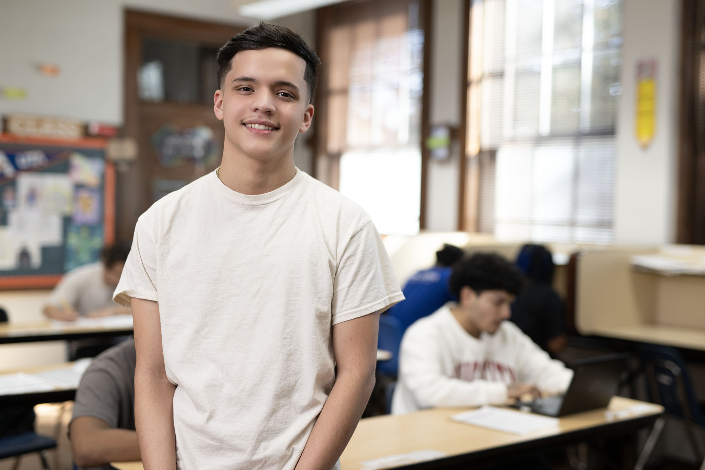 Smiling student standing in a high school classroom