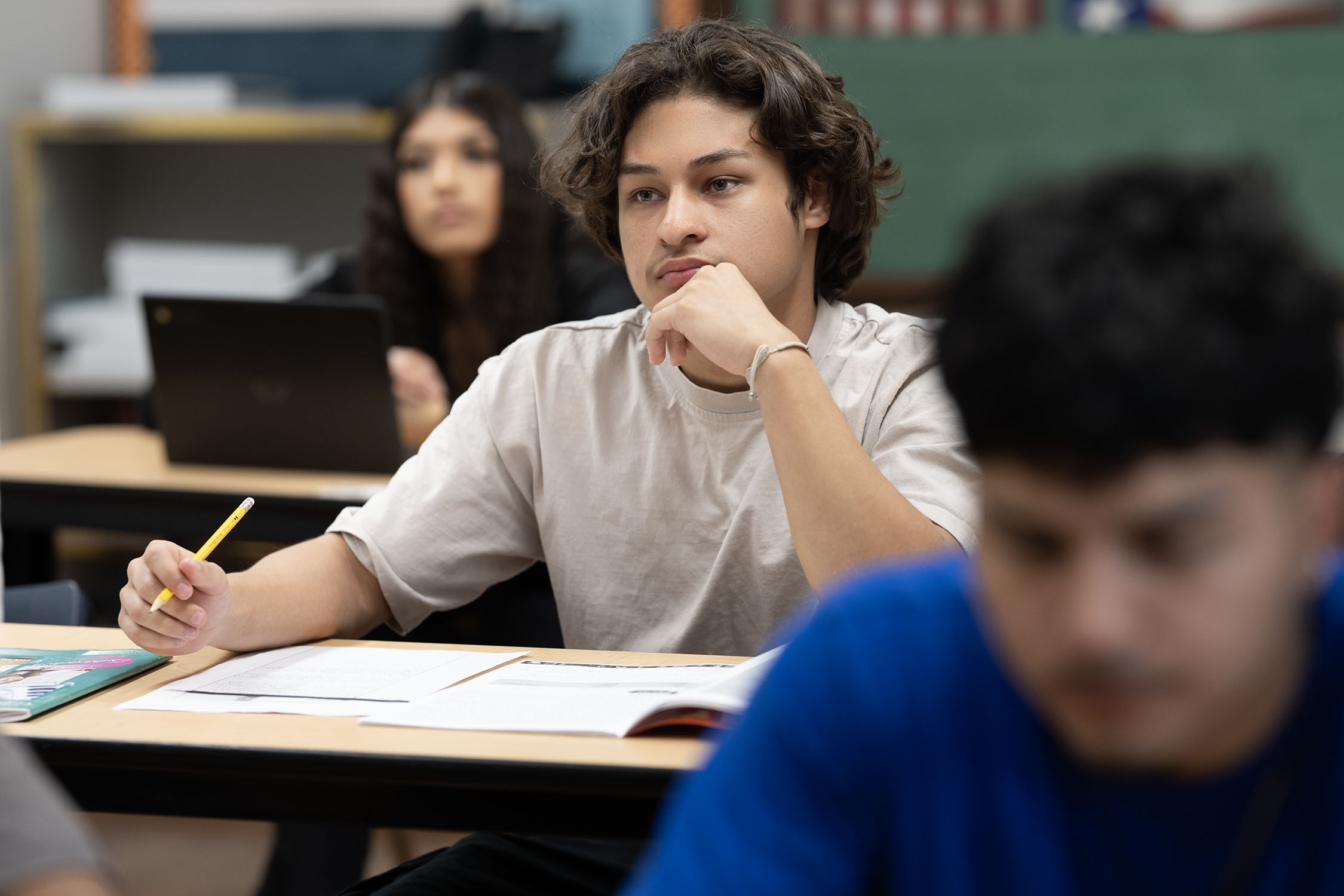 Teenage student thinking intently in classroom setting.