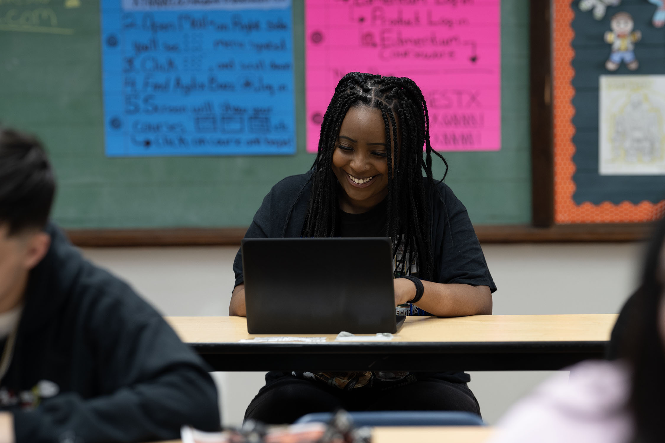 Smiling woman using laptop in classroom setting