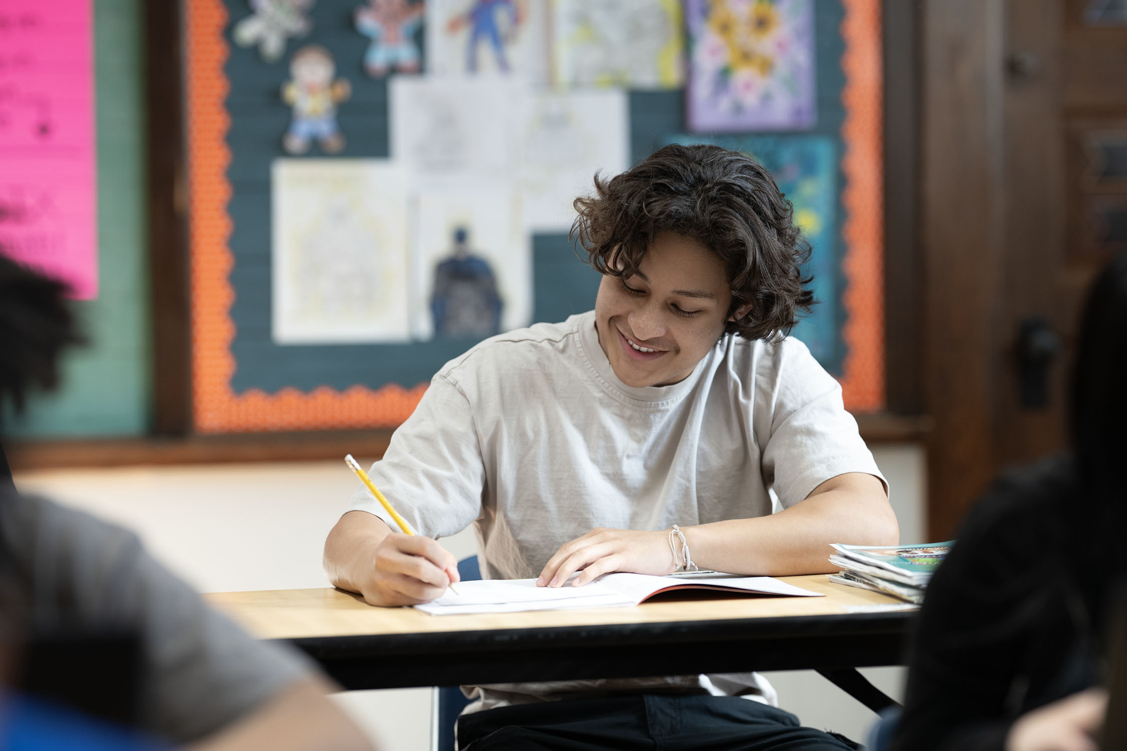 Student writing in notebook during class session