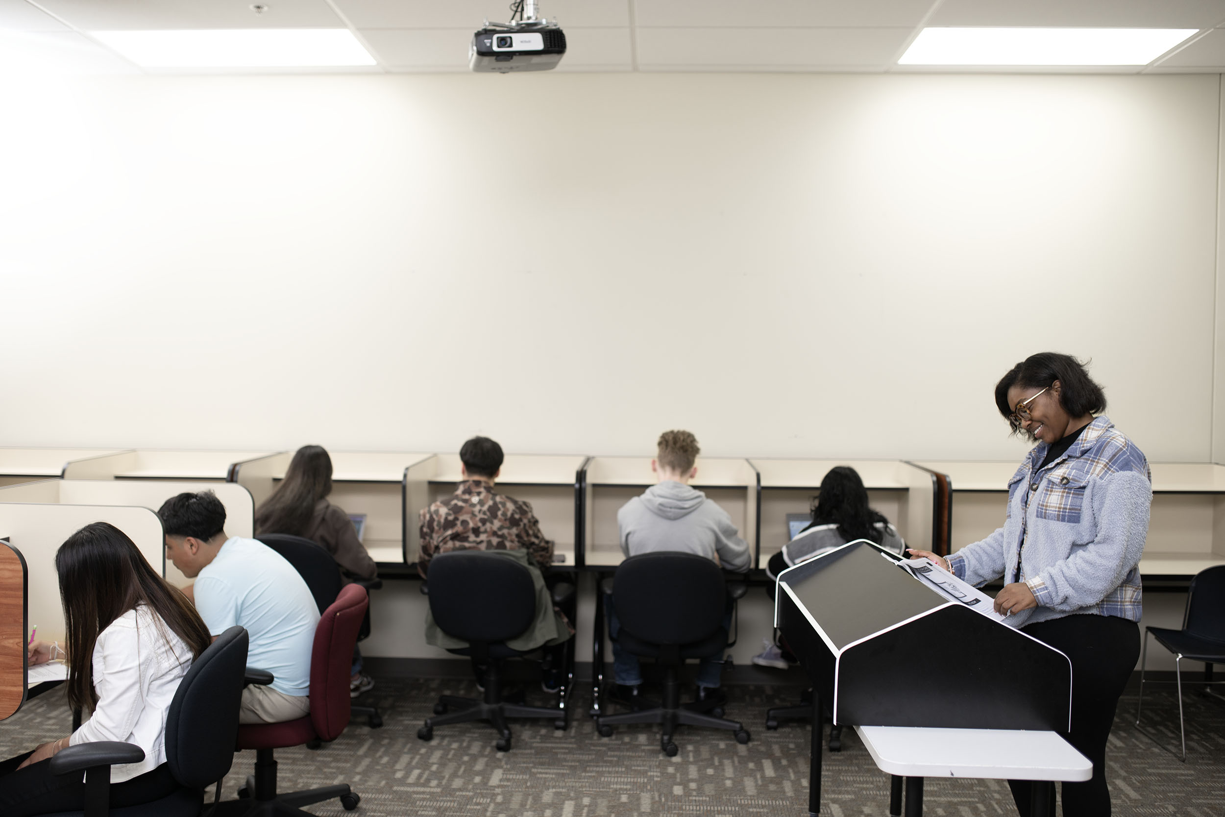 Instructor monitoring students taking test in classroom