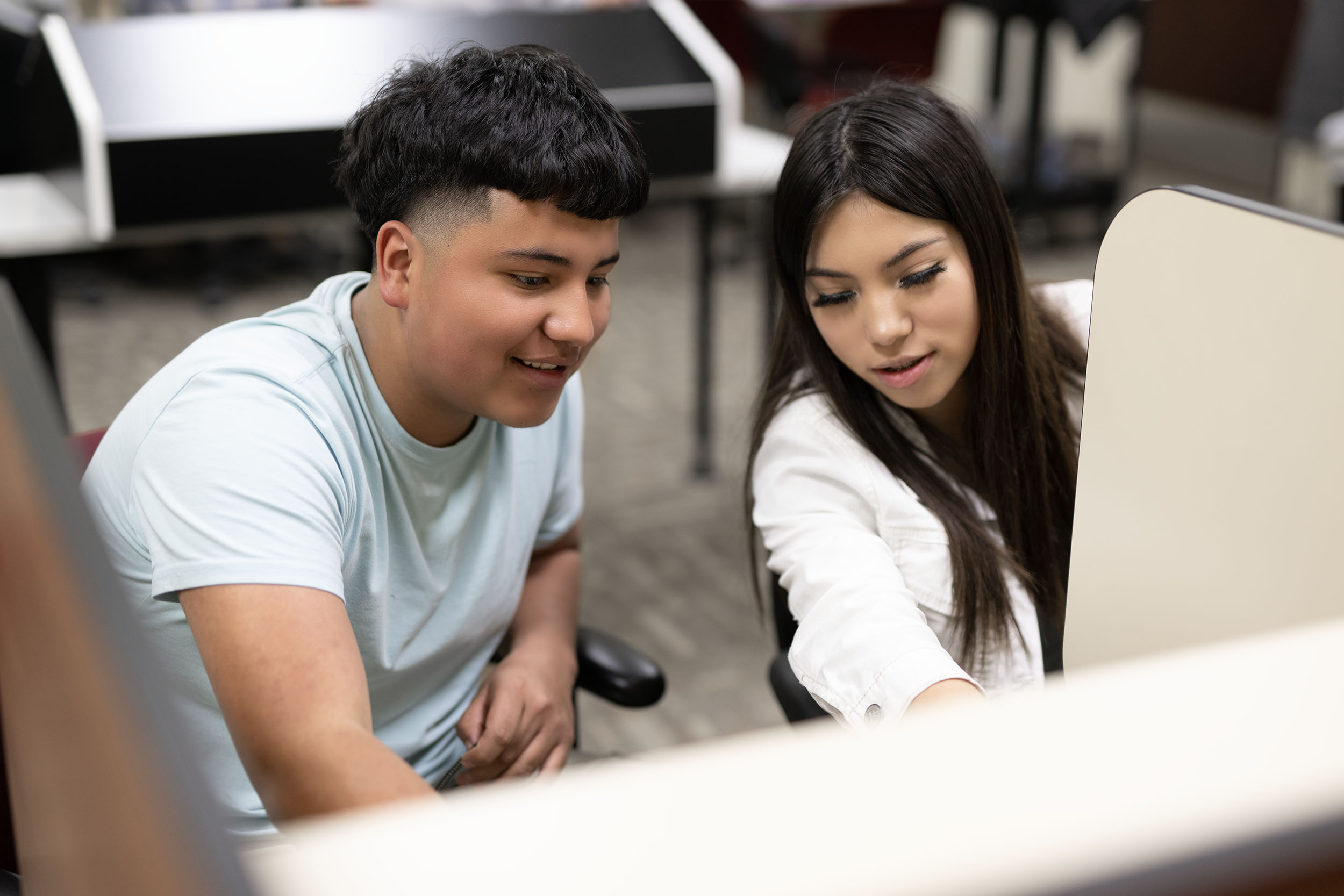 Two students collaborating on a project using computer