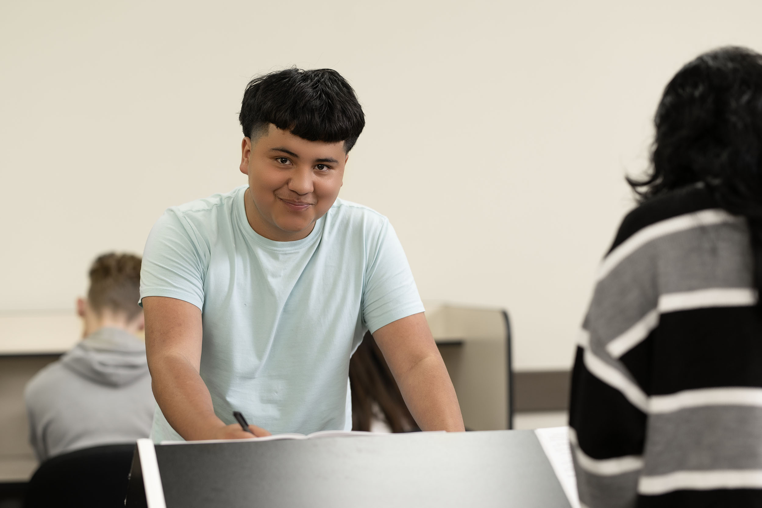 Young male student smiling in classroom setting