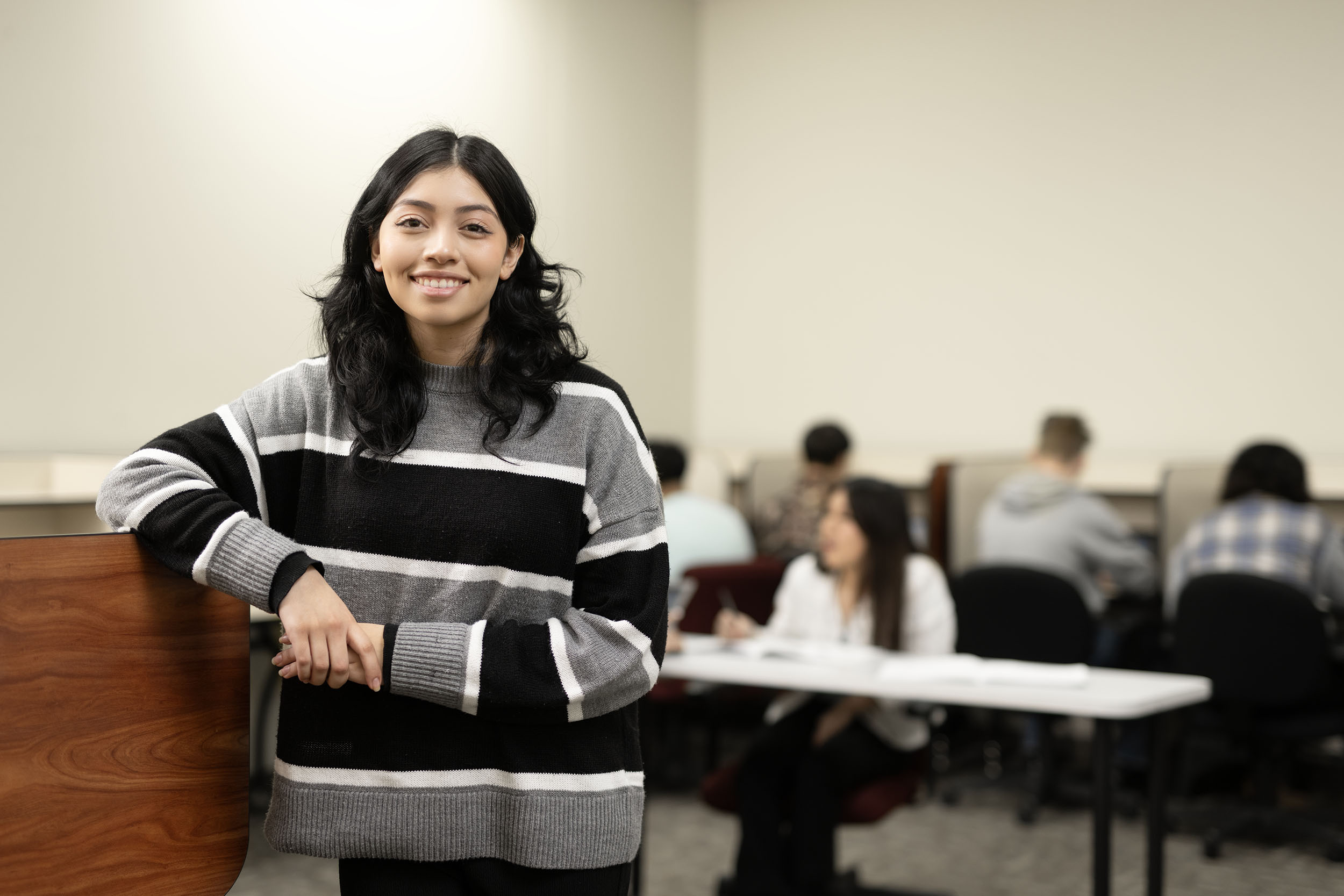 Confident student standing in classroom setting.