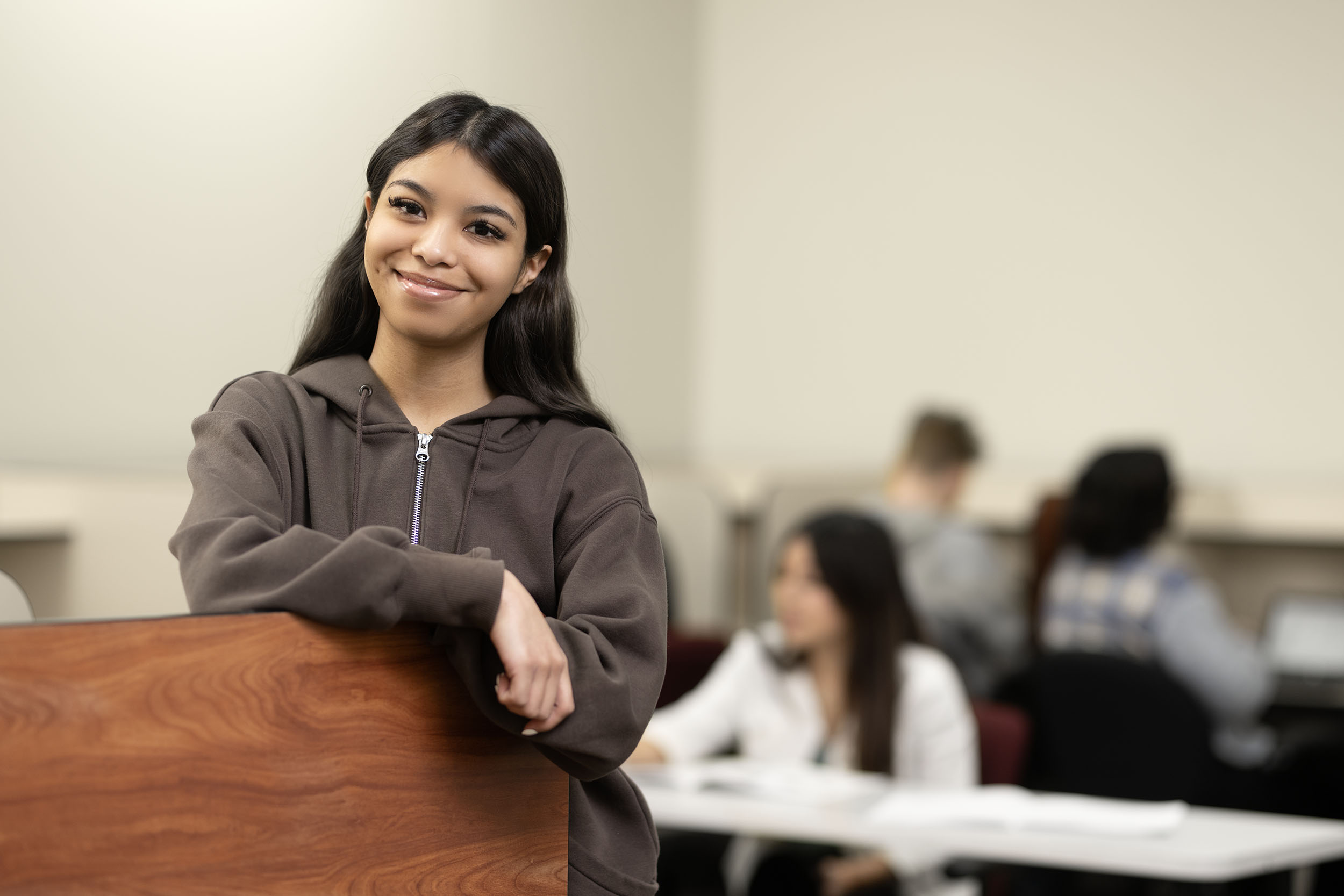 Confident female student standing in classroom setting.