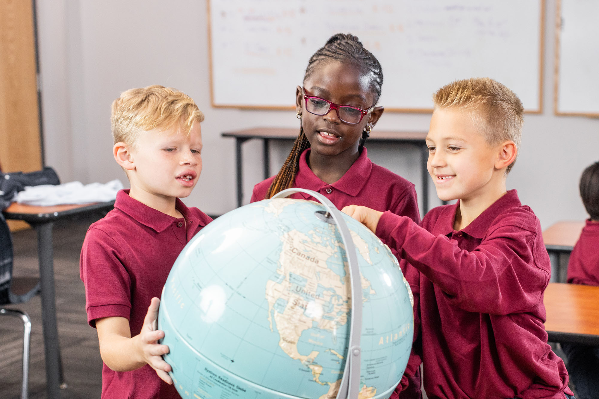 School children in uniform learning with globe.