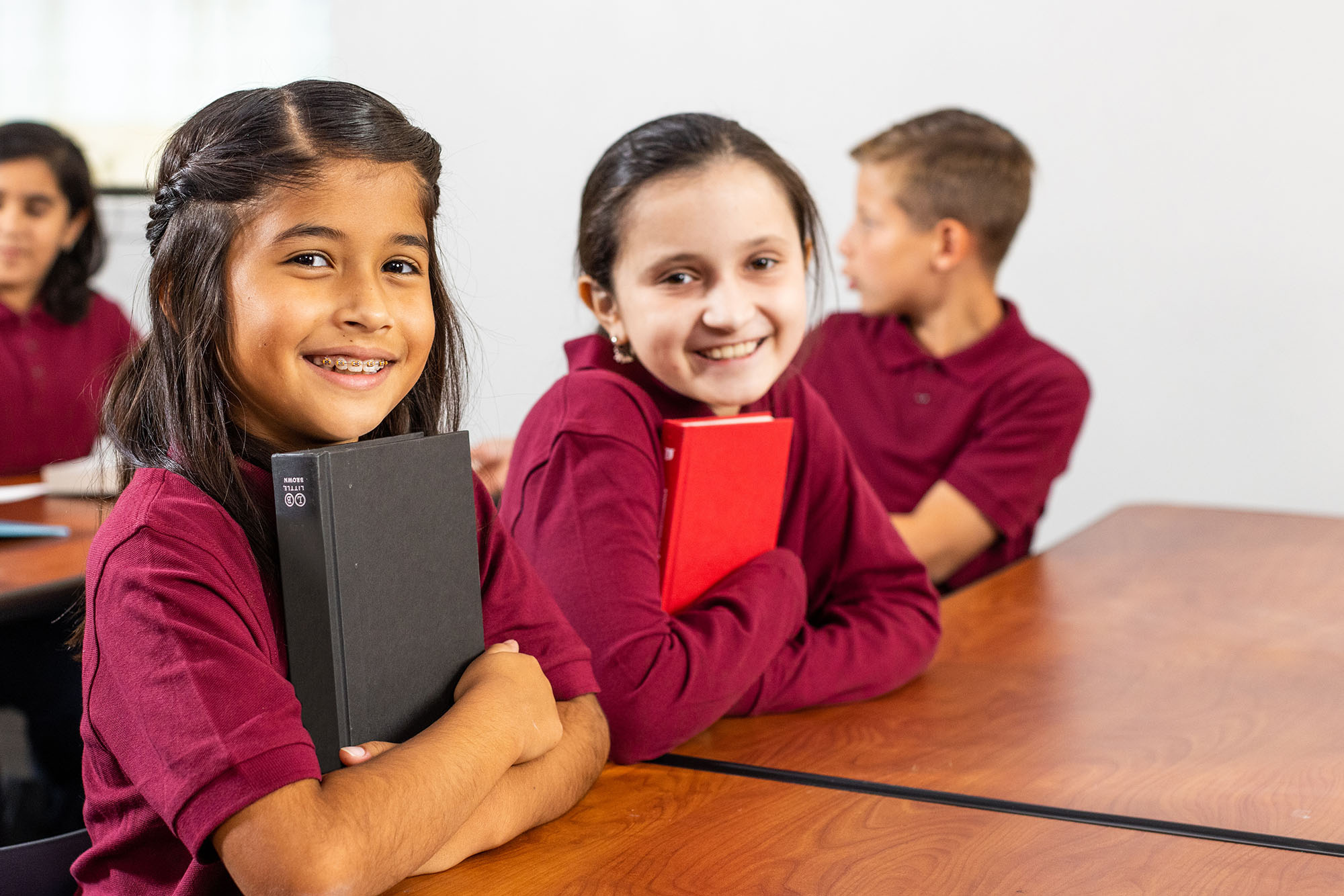 Smiling students holding books in classroom