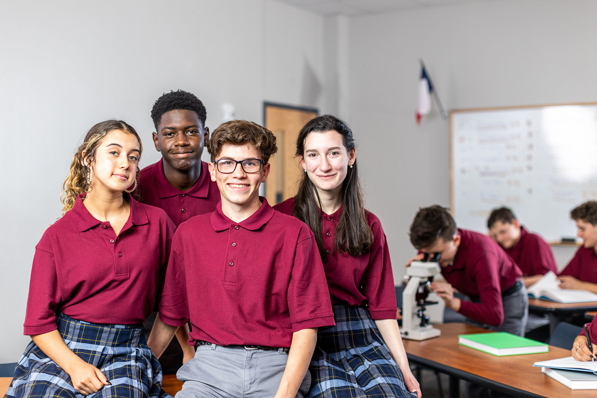 High school students smiling in uniform in classroom
