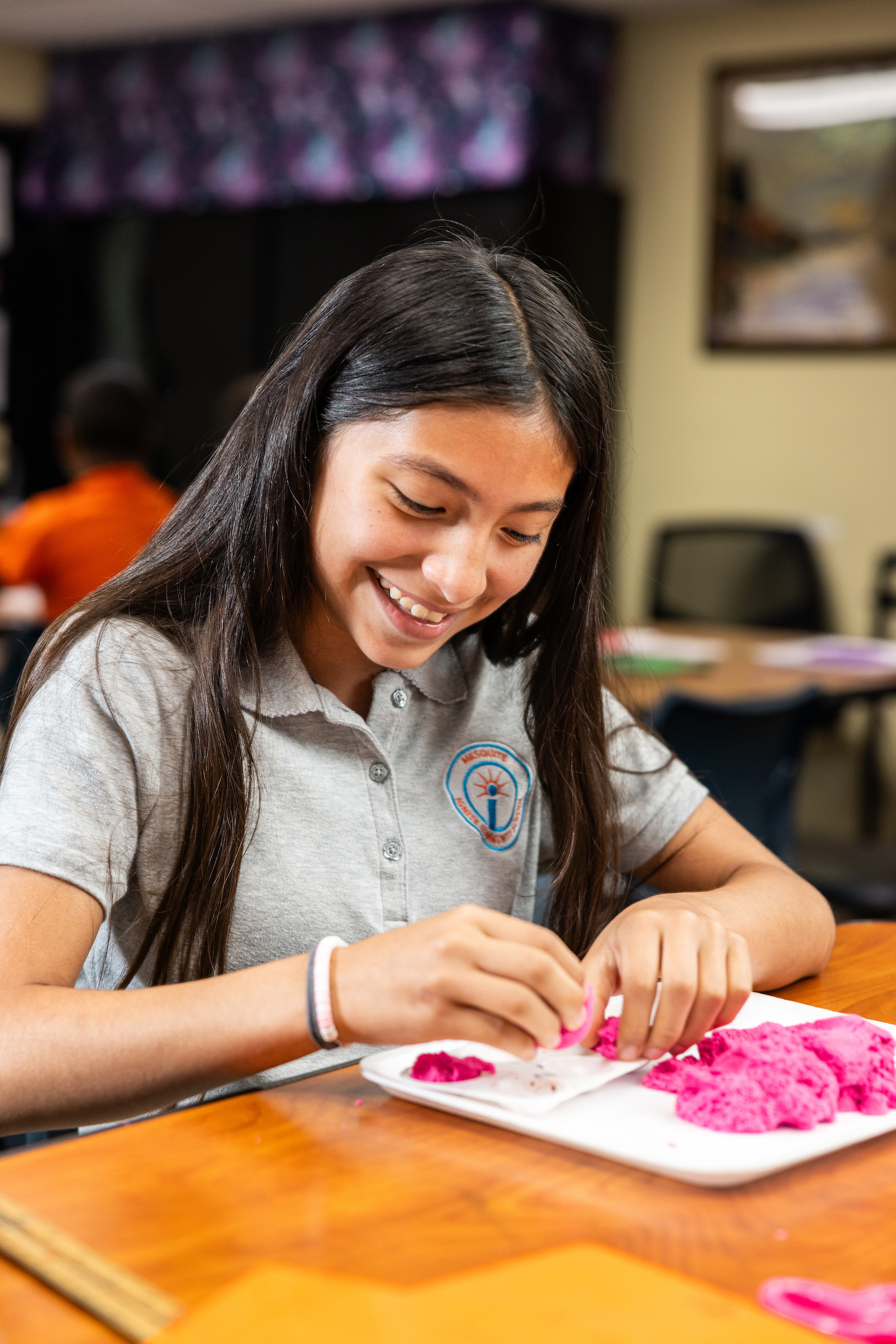 Girl crafting with pink modeling clay at table