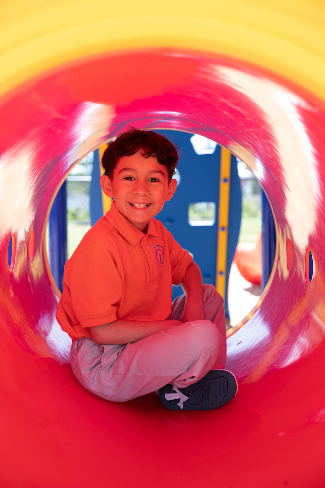 Child smiling inside colorful playground tunnel slide
