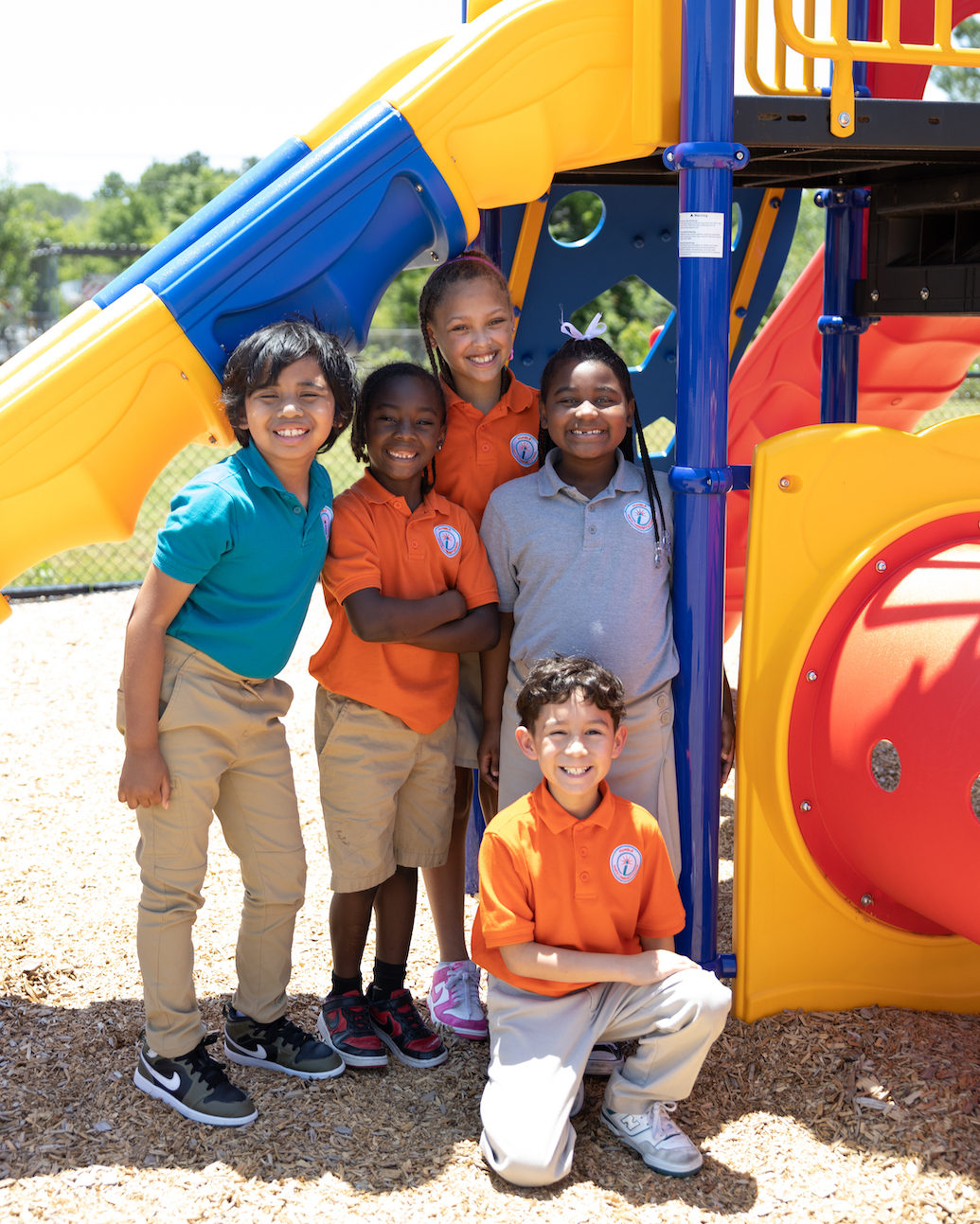 Children smiling together at colorful playground equipment