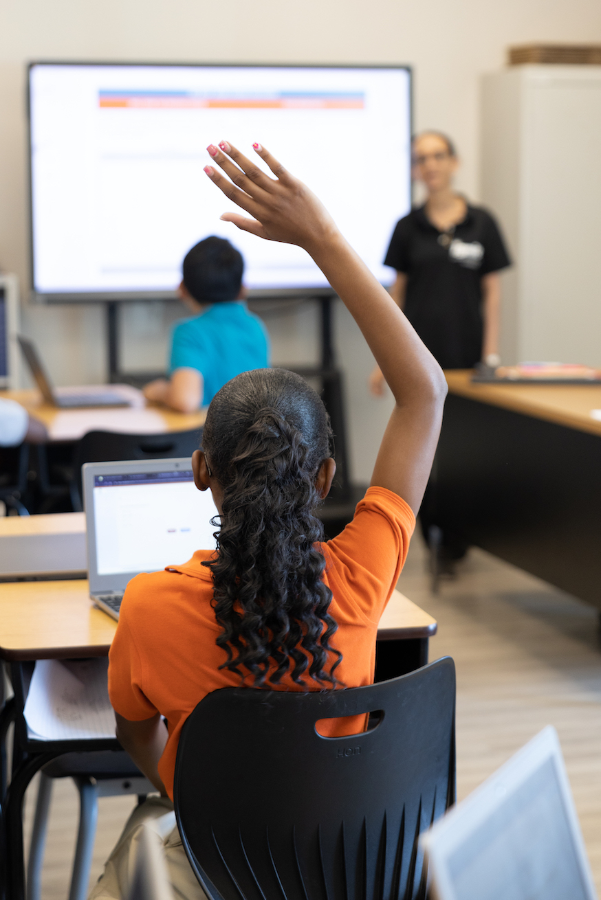 Student raising hand in a classroom setting